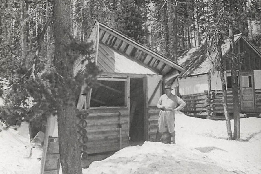 man standing in front of an old cabin